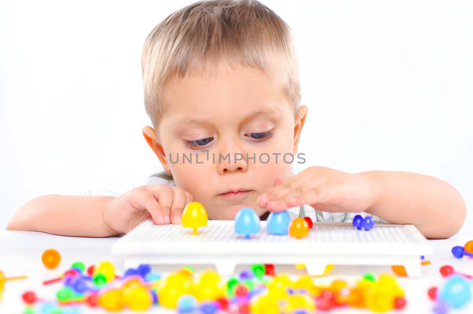Little cute boy playing with multicolored mosaic by maxoliki