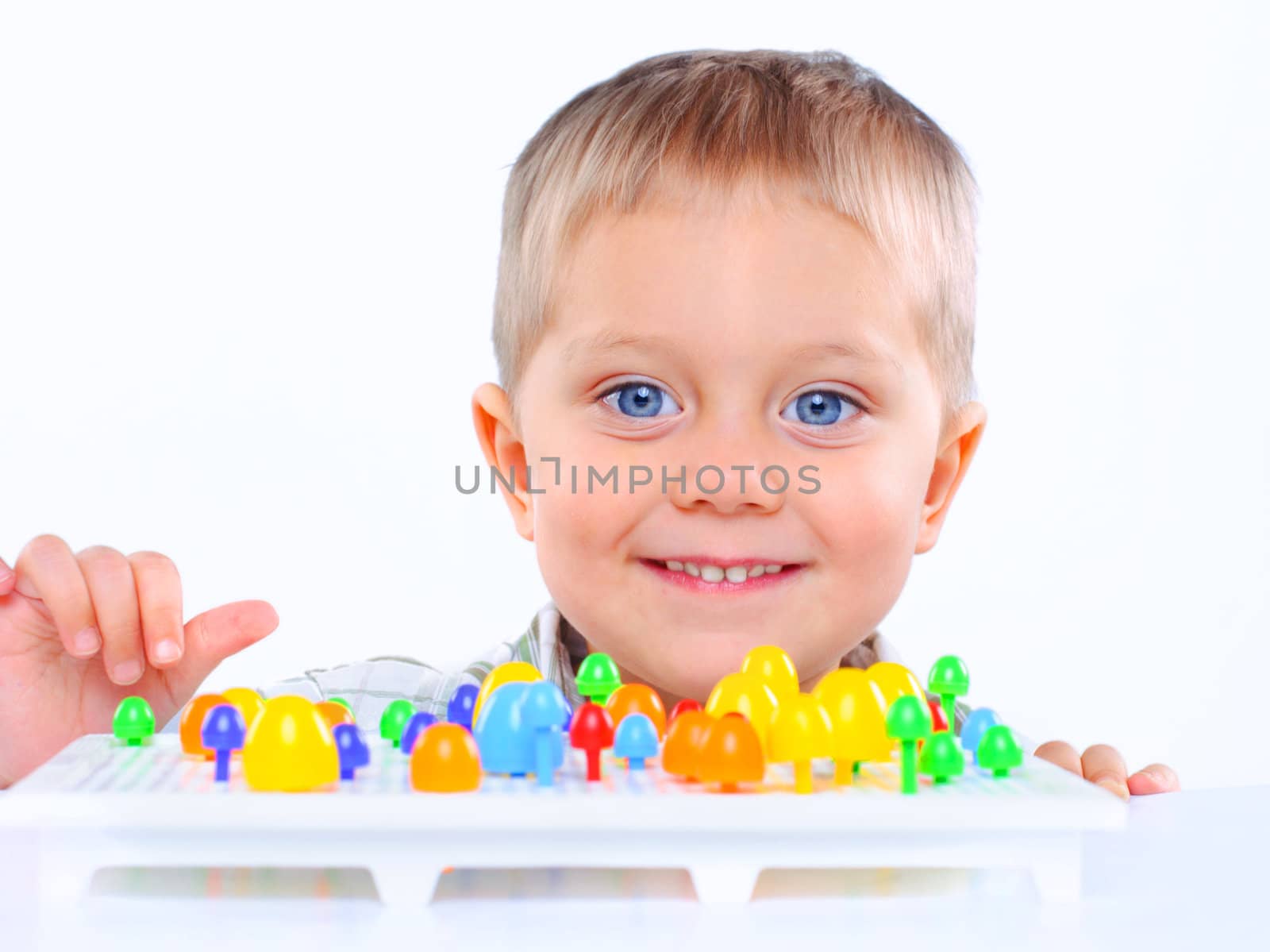 Little cute boy playing with multicolored mosaic by maxoliki