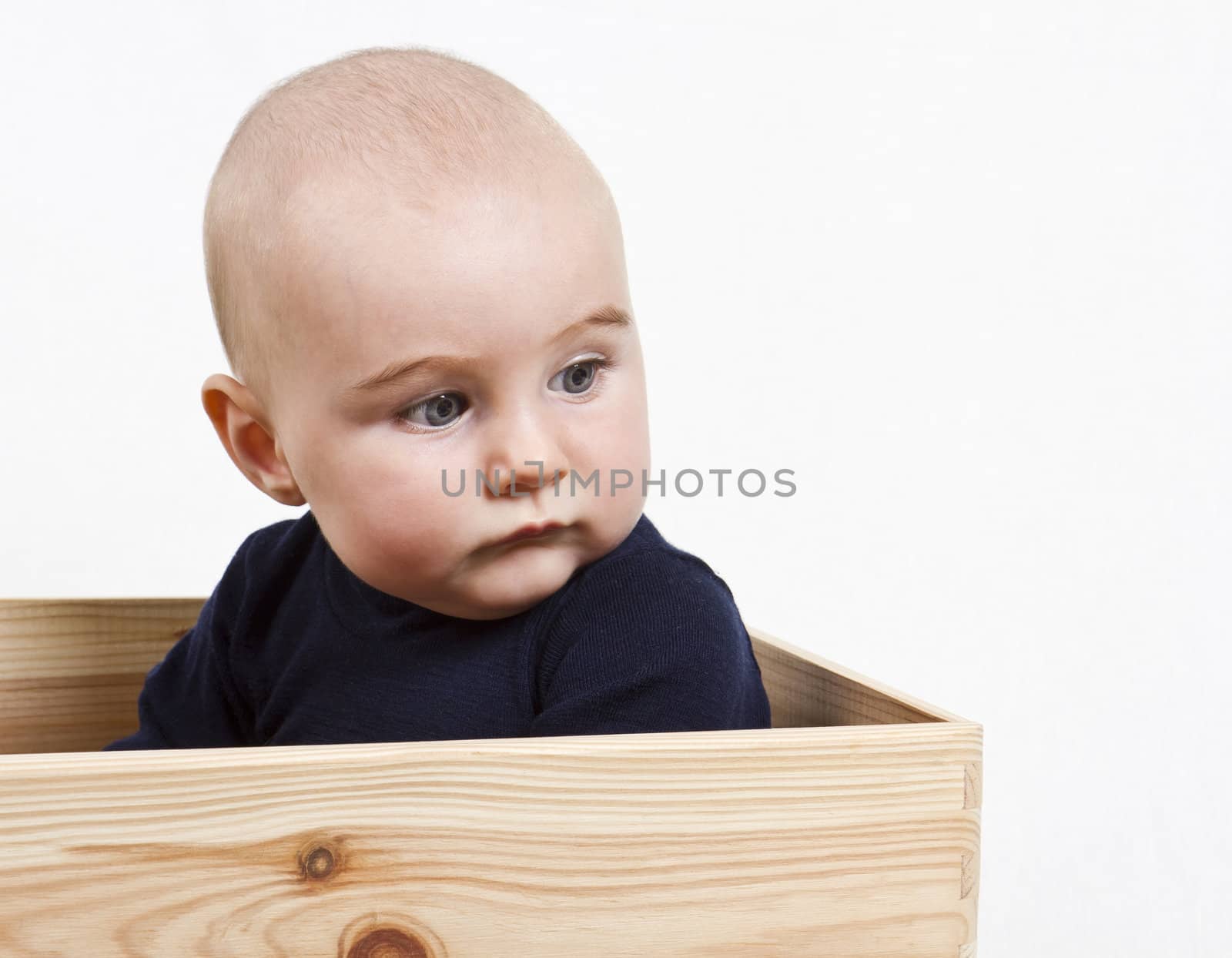 single toddler with dark shirt in wooden box looking to the right.