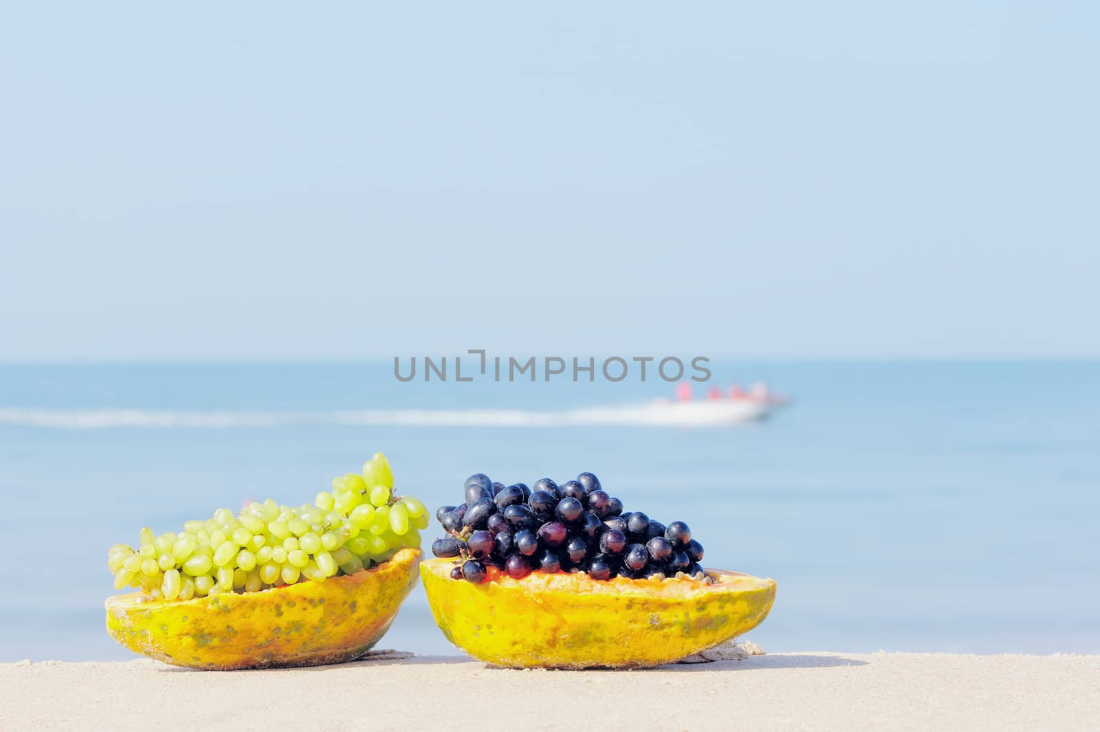 Tropical papaya and grape on the sandy shore