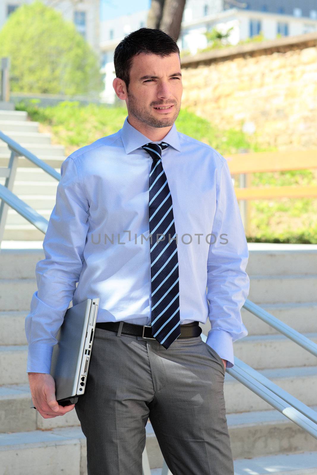 standing businessman waiting outdoor with laptop on stairs