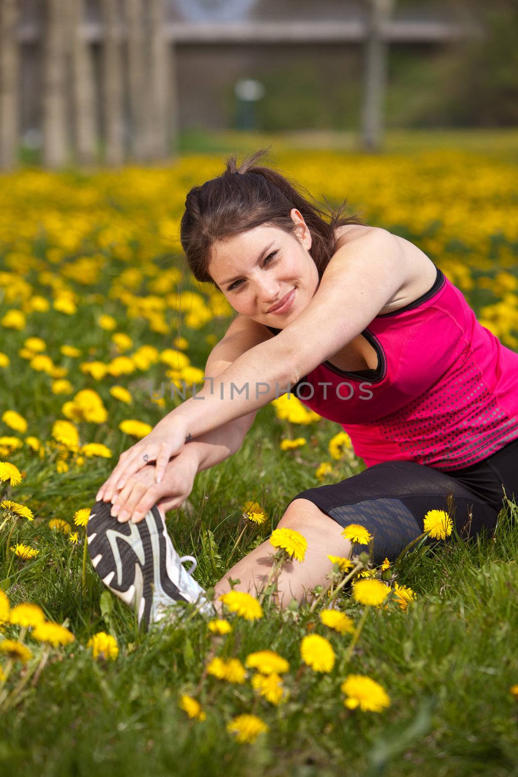 Pretty young woman doing stretch exercises in a field of dandelions