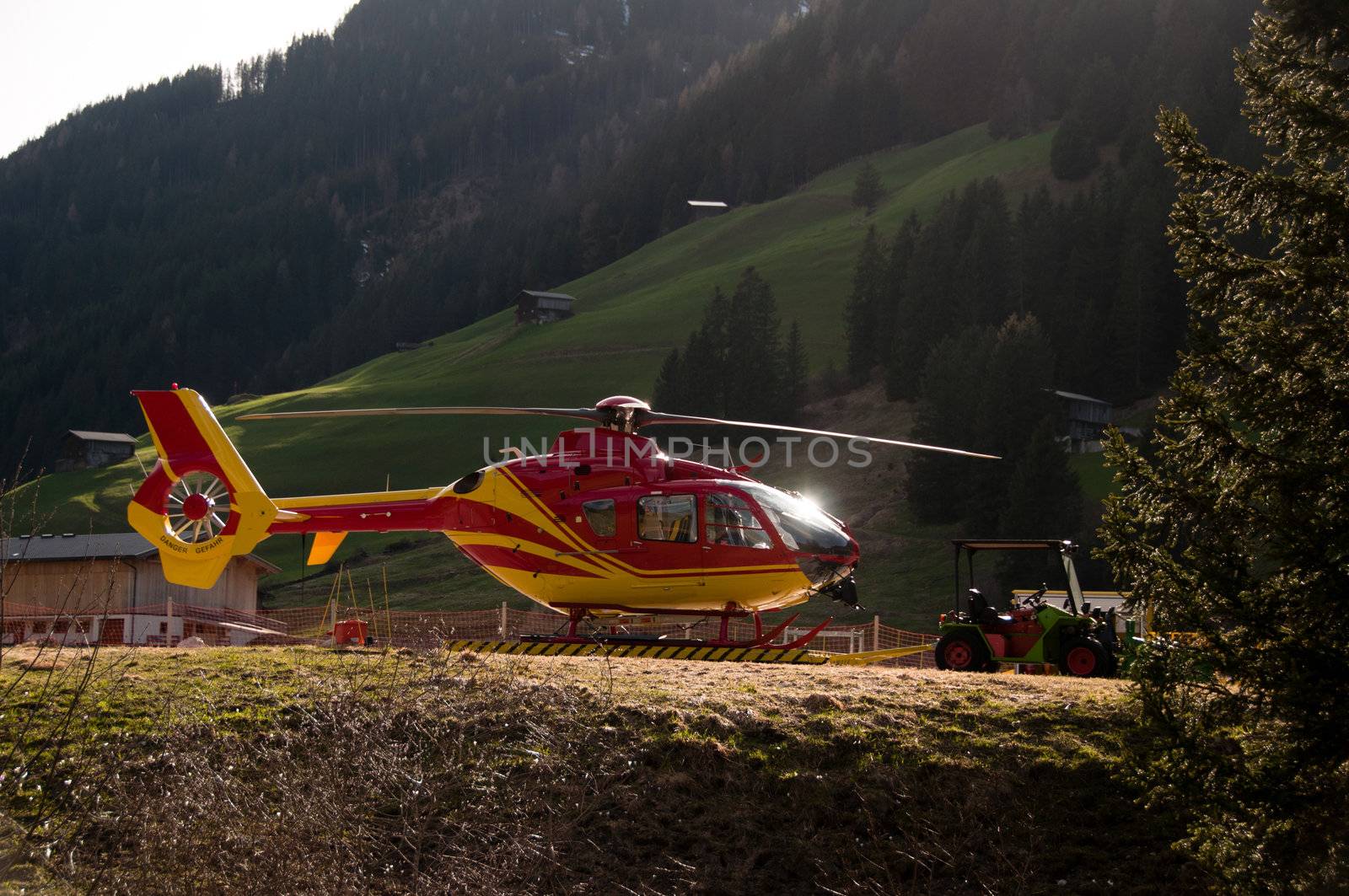 Side Of Grounded Yellow and Red Helicopter At Hangar