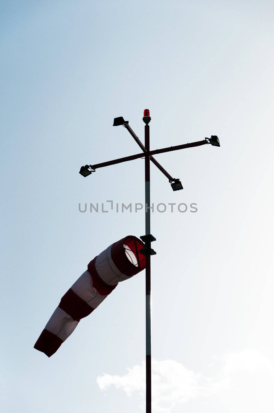 a red white striped wind gauge against cloudy sky