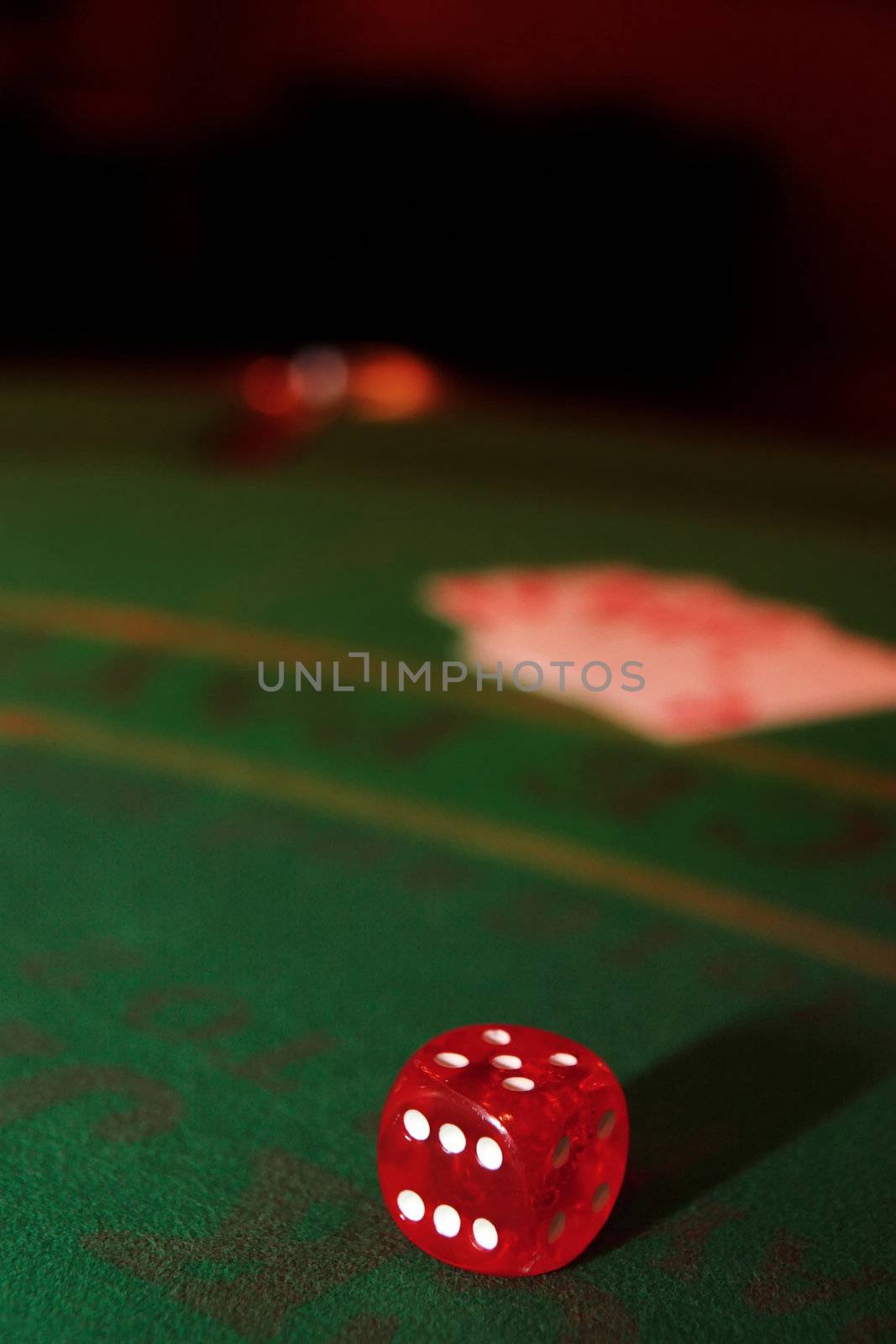 green casino table with dice and a blurred hand of a royal flush in a poker game