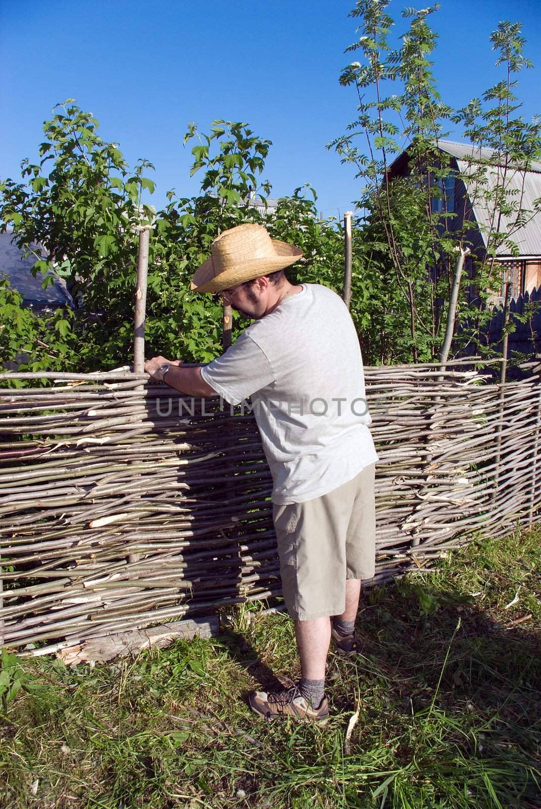 The man builds a wattle fence. The Countryside