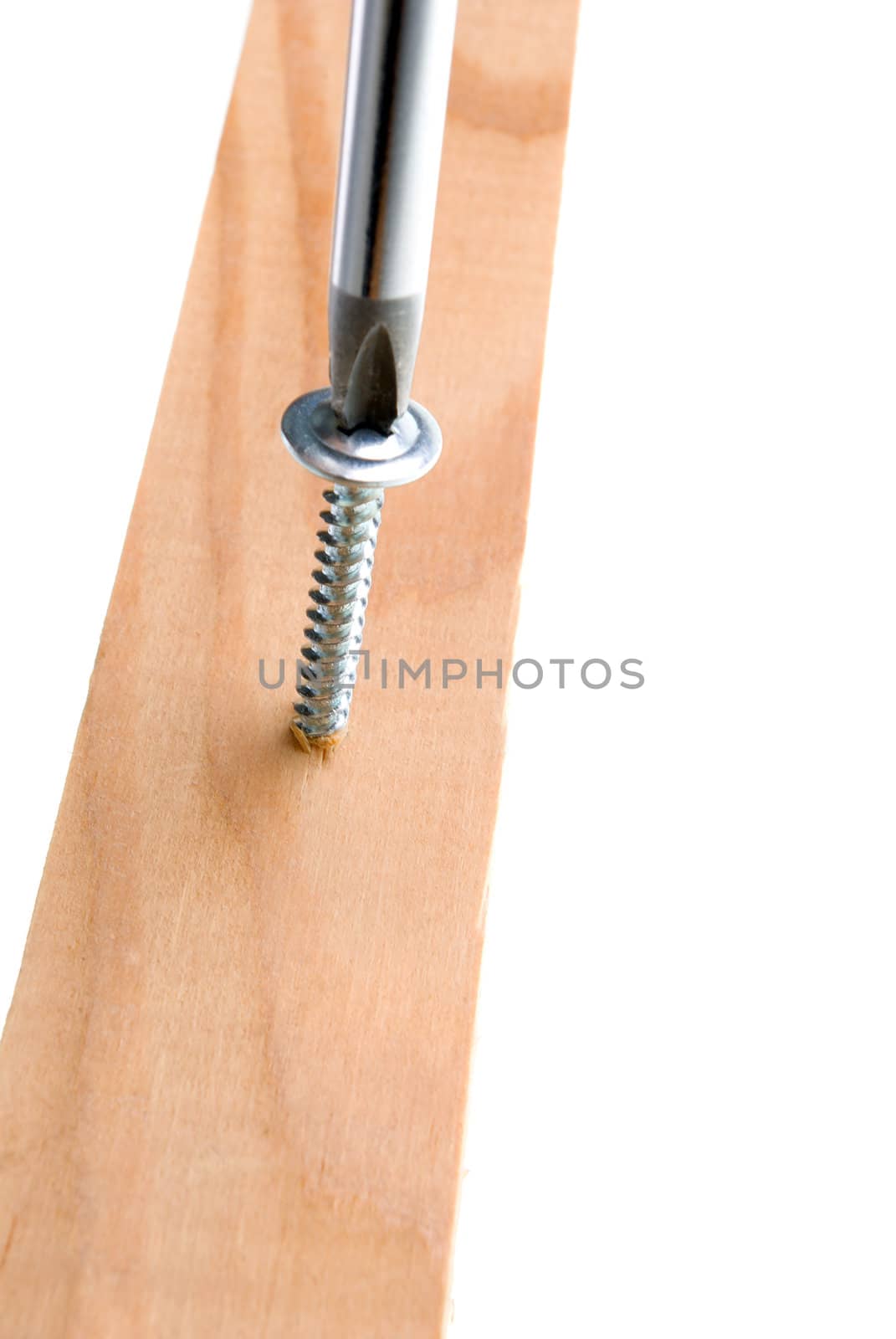 Screwdriver and single screw in board.a,isolated on white background