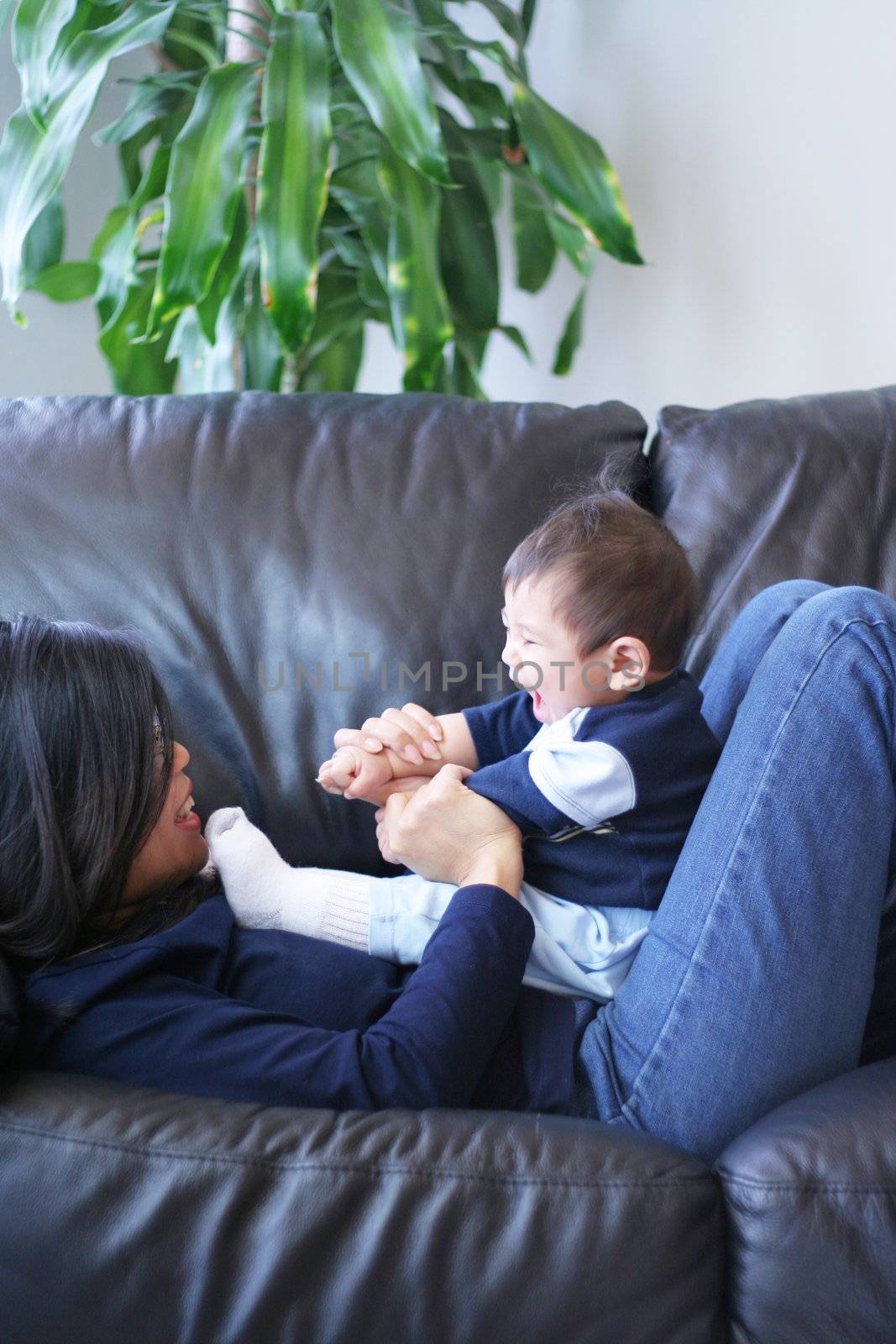 Mother playing with her baby boy on couch