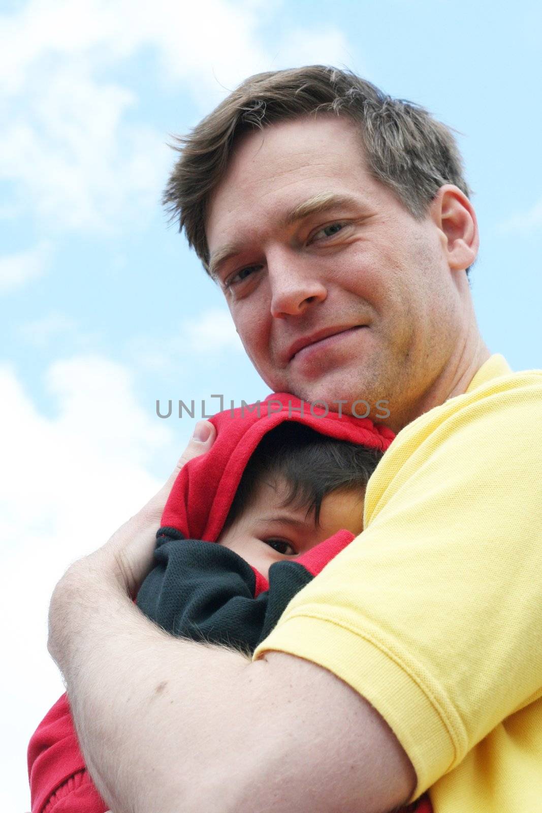 Baby cuddled safely in dad's arms. Father is Scandinavian, baby is multiracial