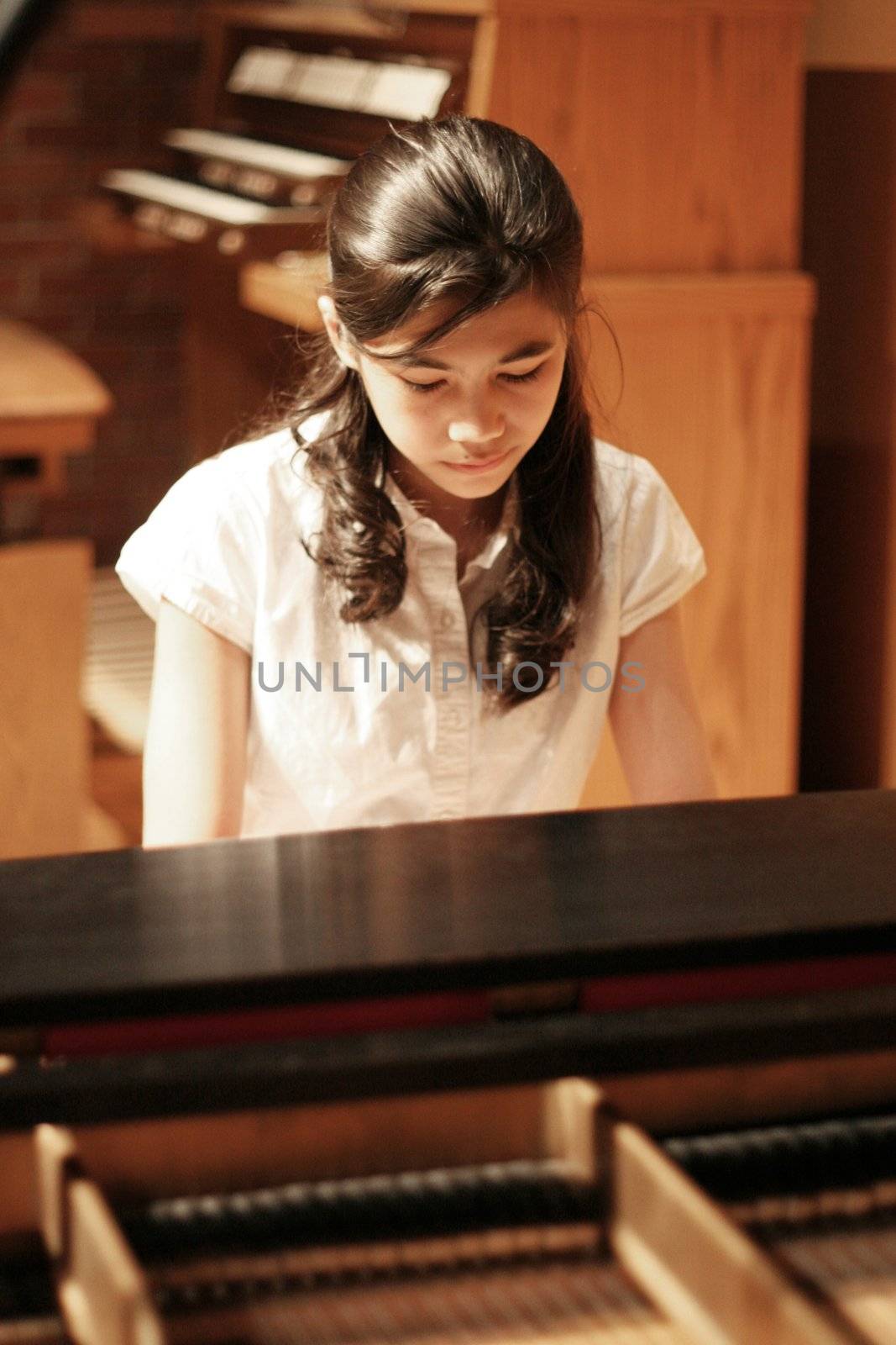 Young teen girl playing piano at recital