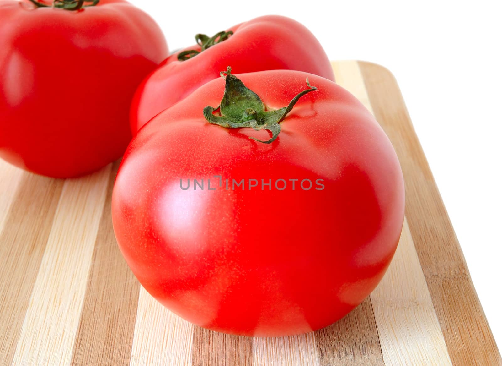 Vegetables (few tomatos) on bamboo cutting board.