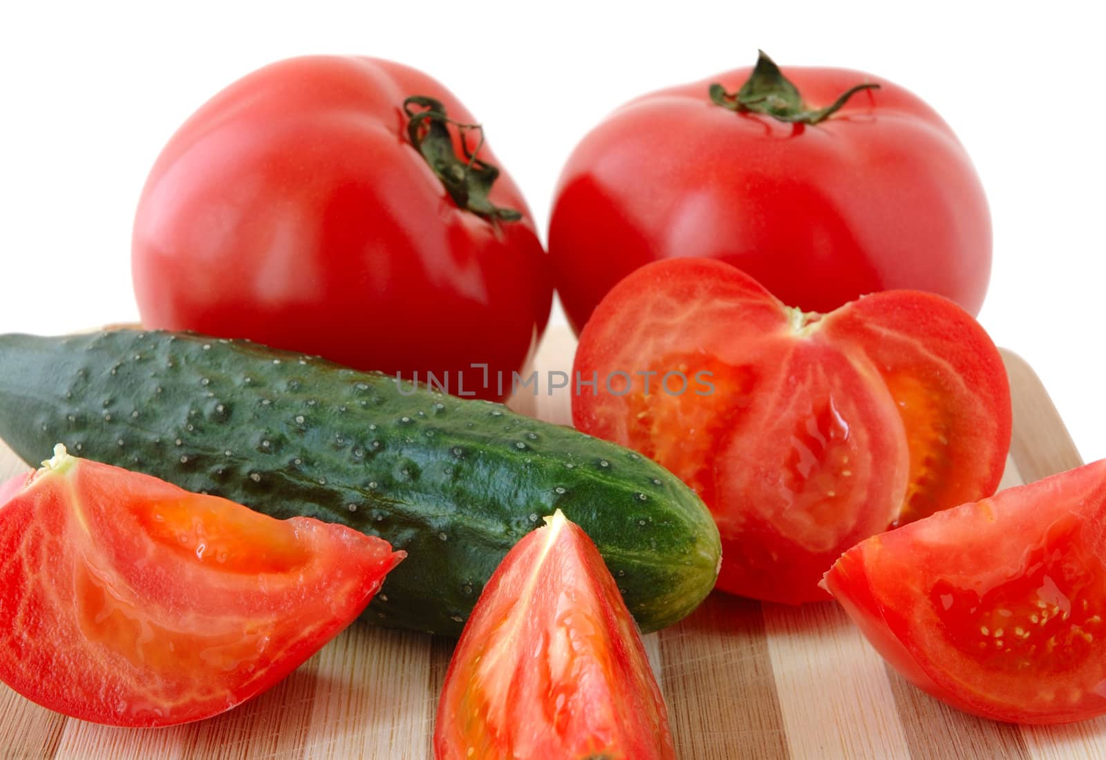 Vegetables (tomatos and cucumber) on bamboo cutting board.