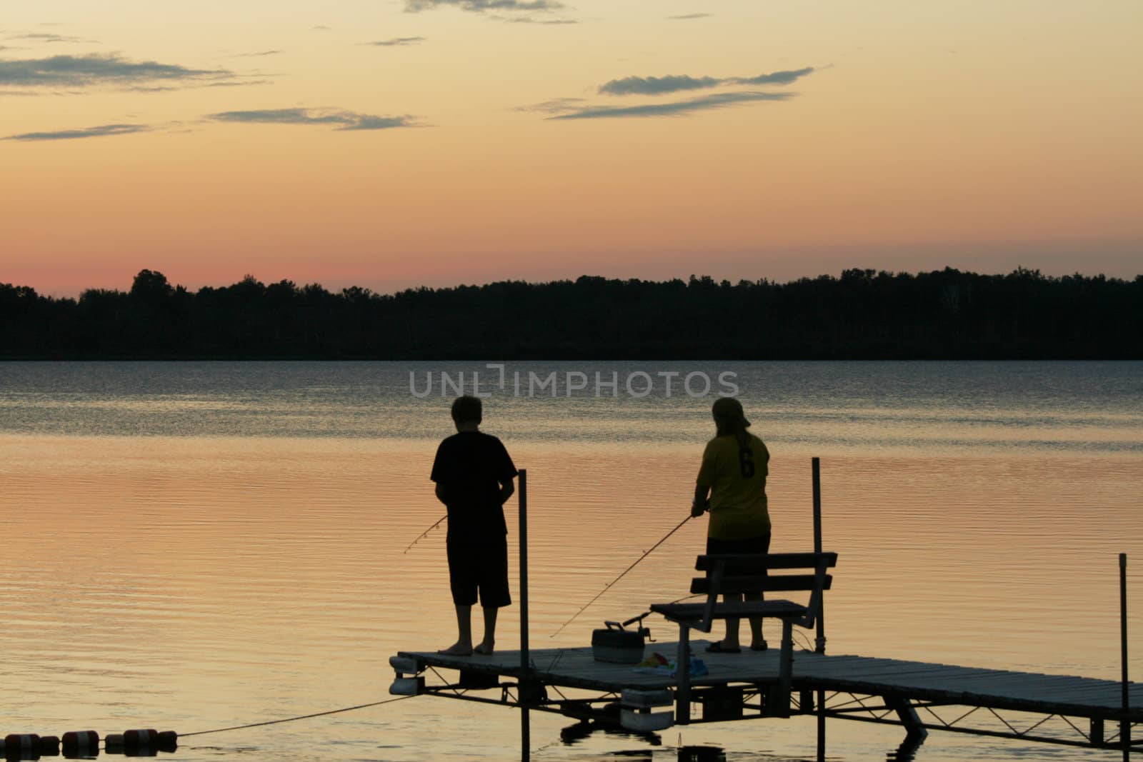 Silhouette of children fishing at sunset