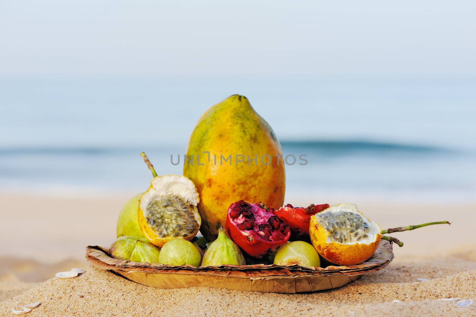 Exotic tropical fruit on the leaves plate, on the sandy beach