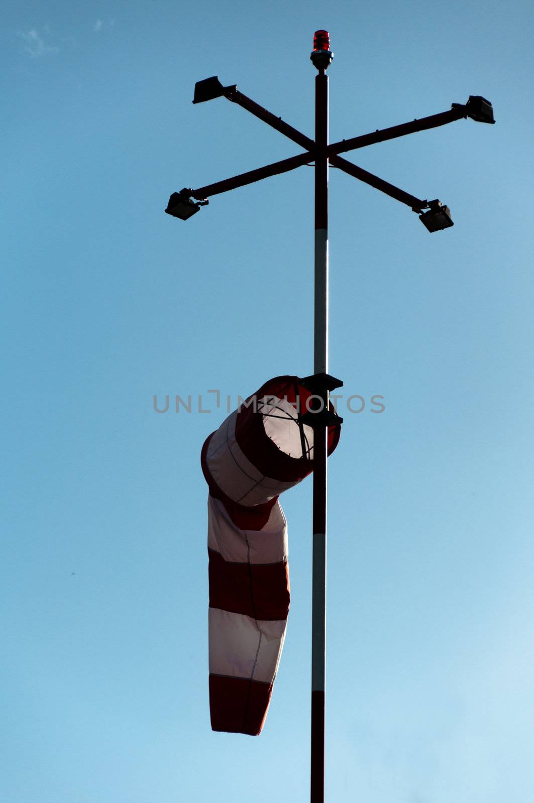 a red white striped wind gauge against cloudy sky