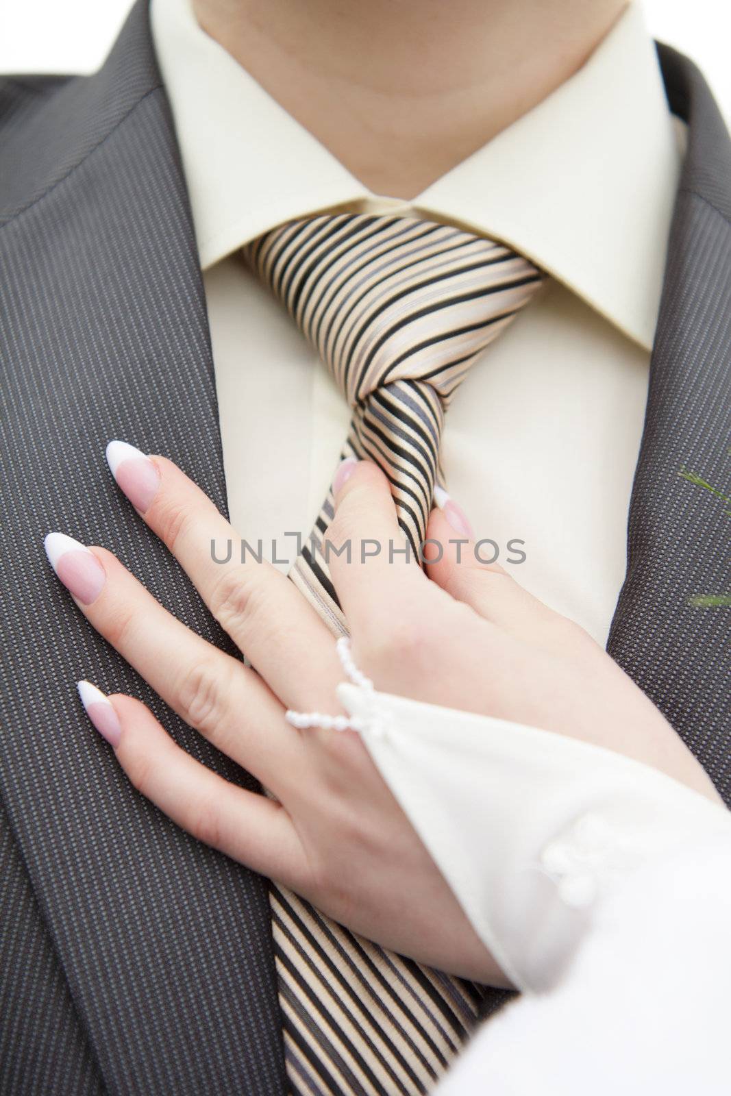 beautiful bride holds the hand of the groom's tie
