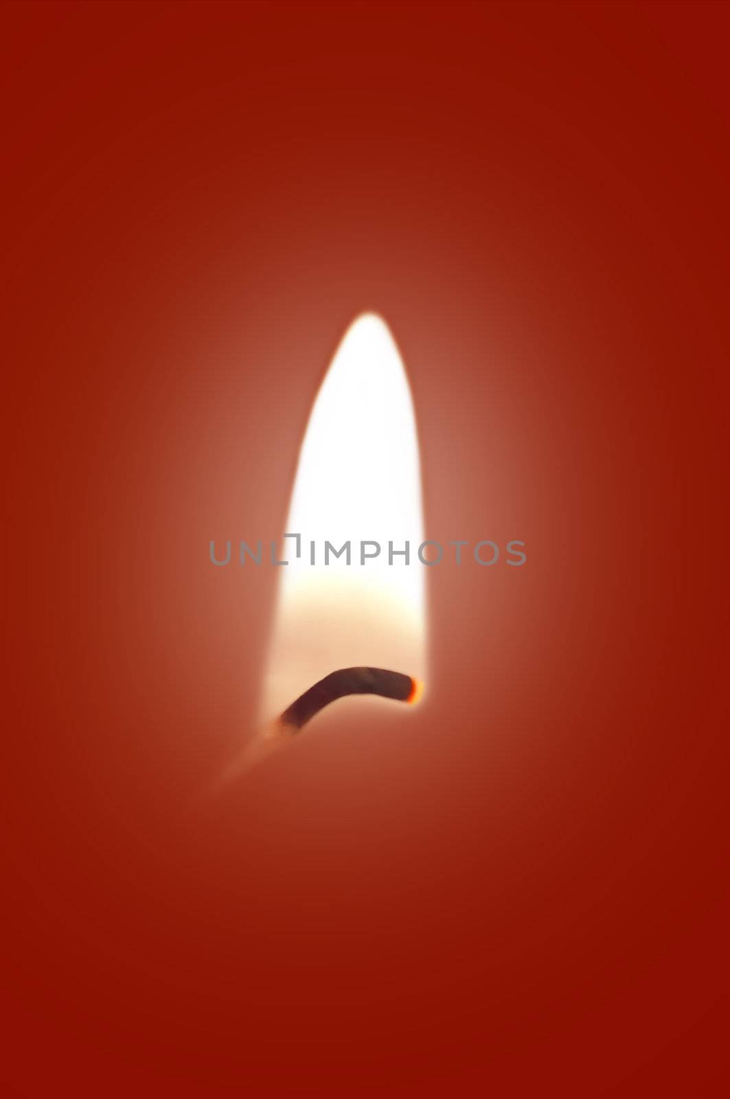 Close up on a single ignited candle wick against a red background.