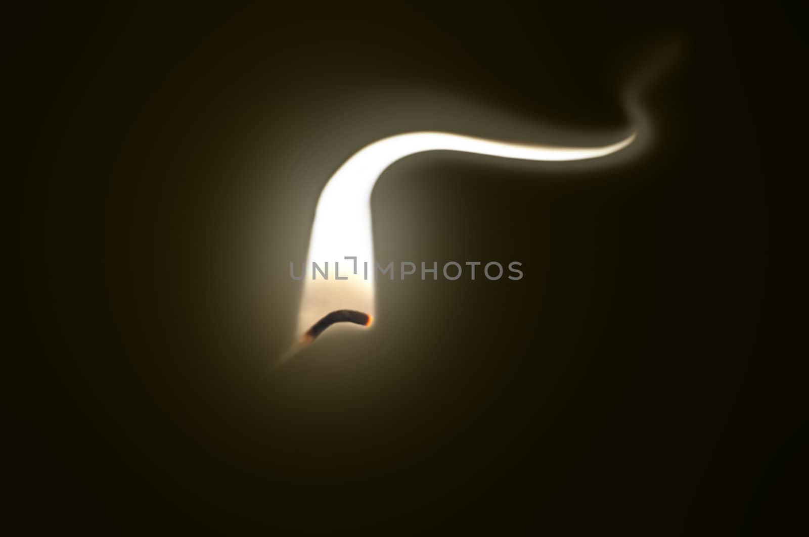 Close up on an ignited candle wick with extended flame against a black background.