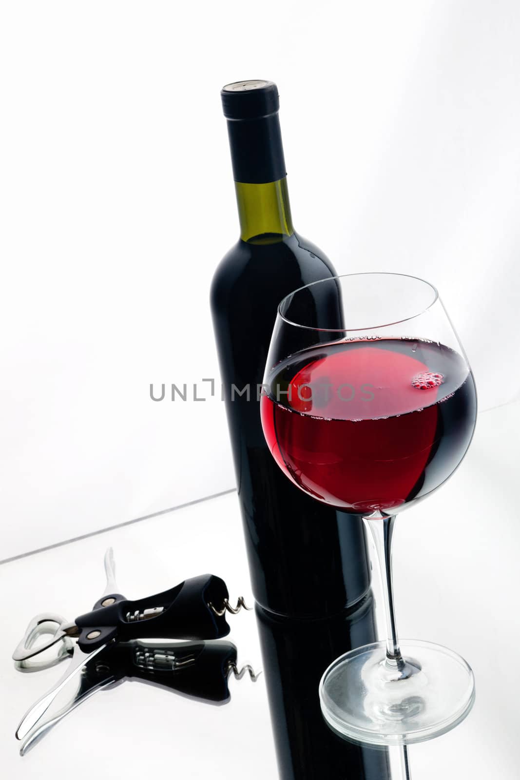 Still-life with bottle and glass of red wine over white background.