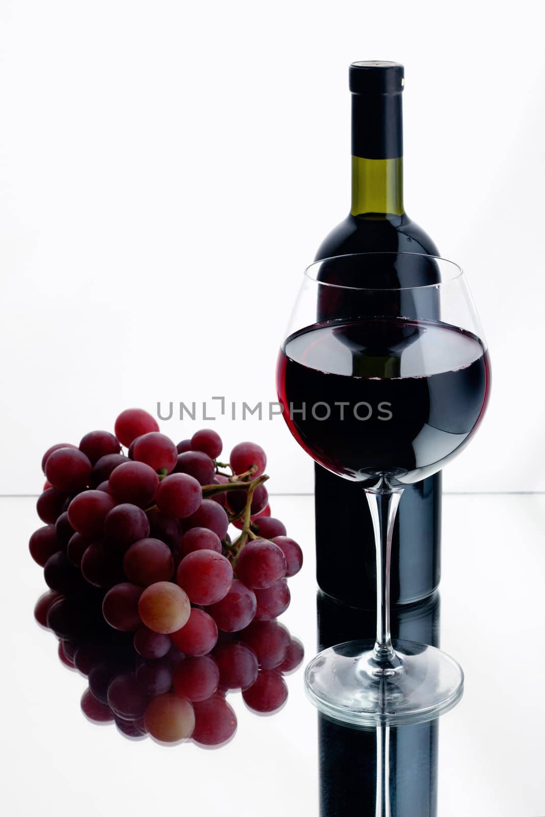 Still-life with bottle and glass of red wine over white background.