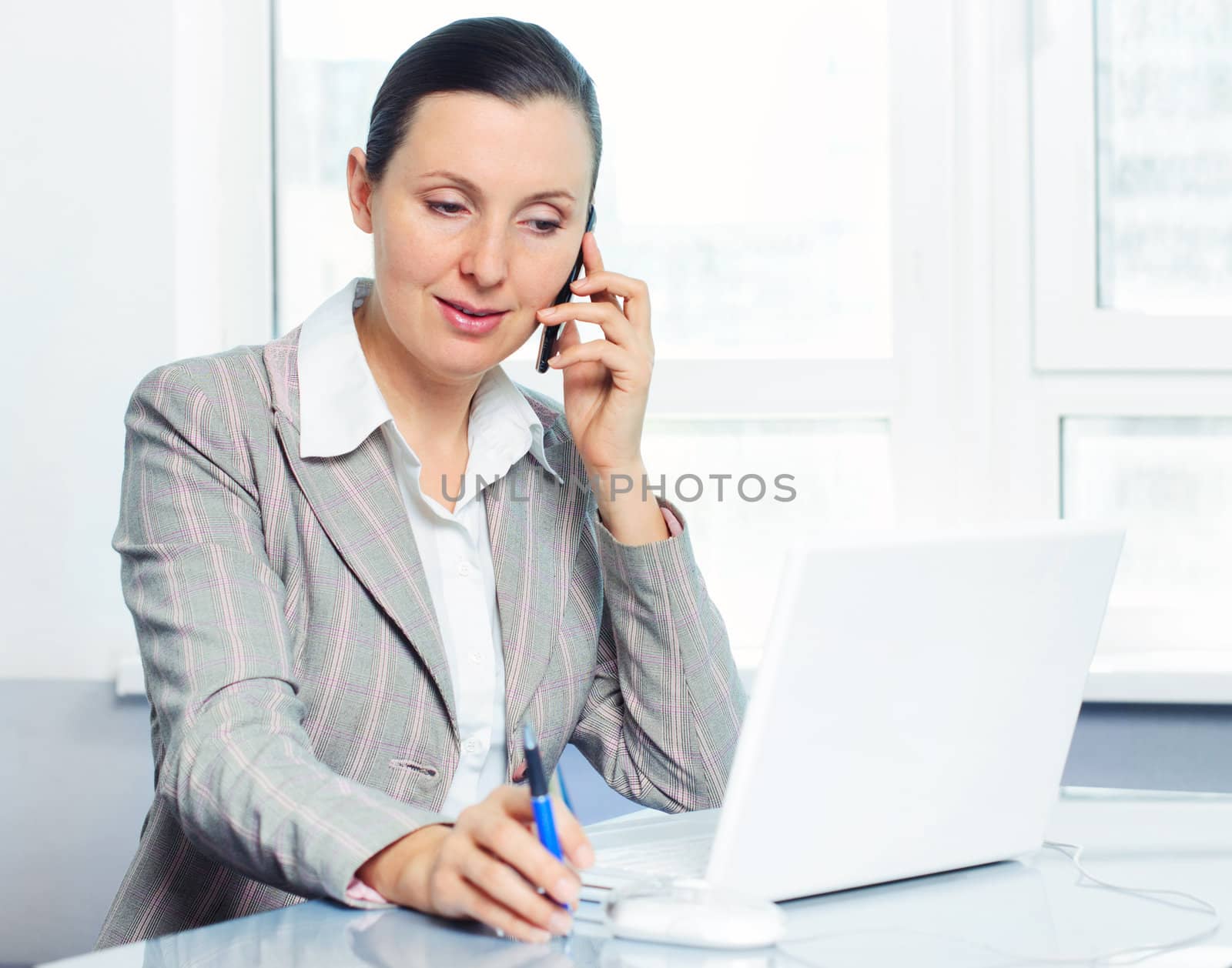 Attractive smiling young business woman using laptop at work desk