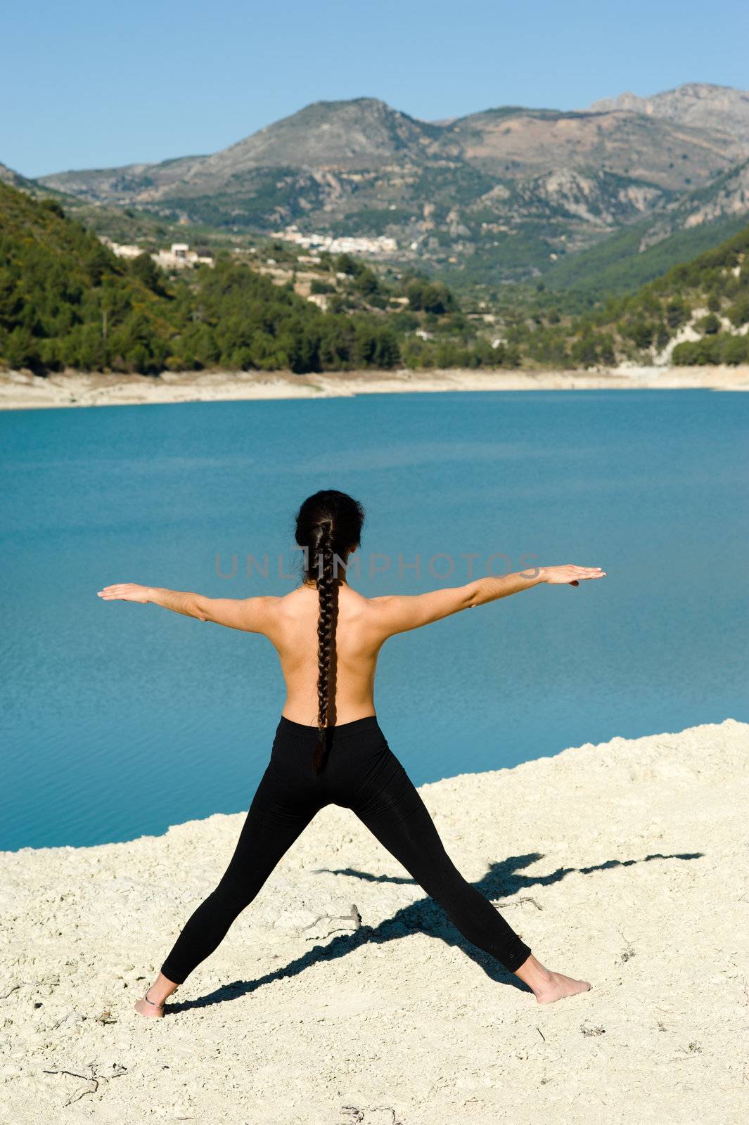 Young woman at early morning yoga on the shores of  a lake