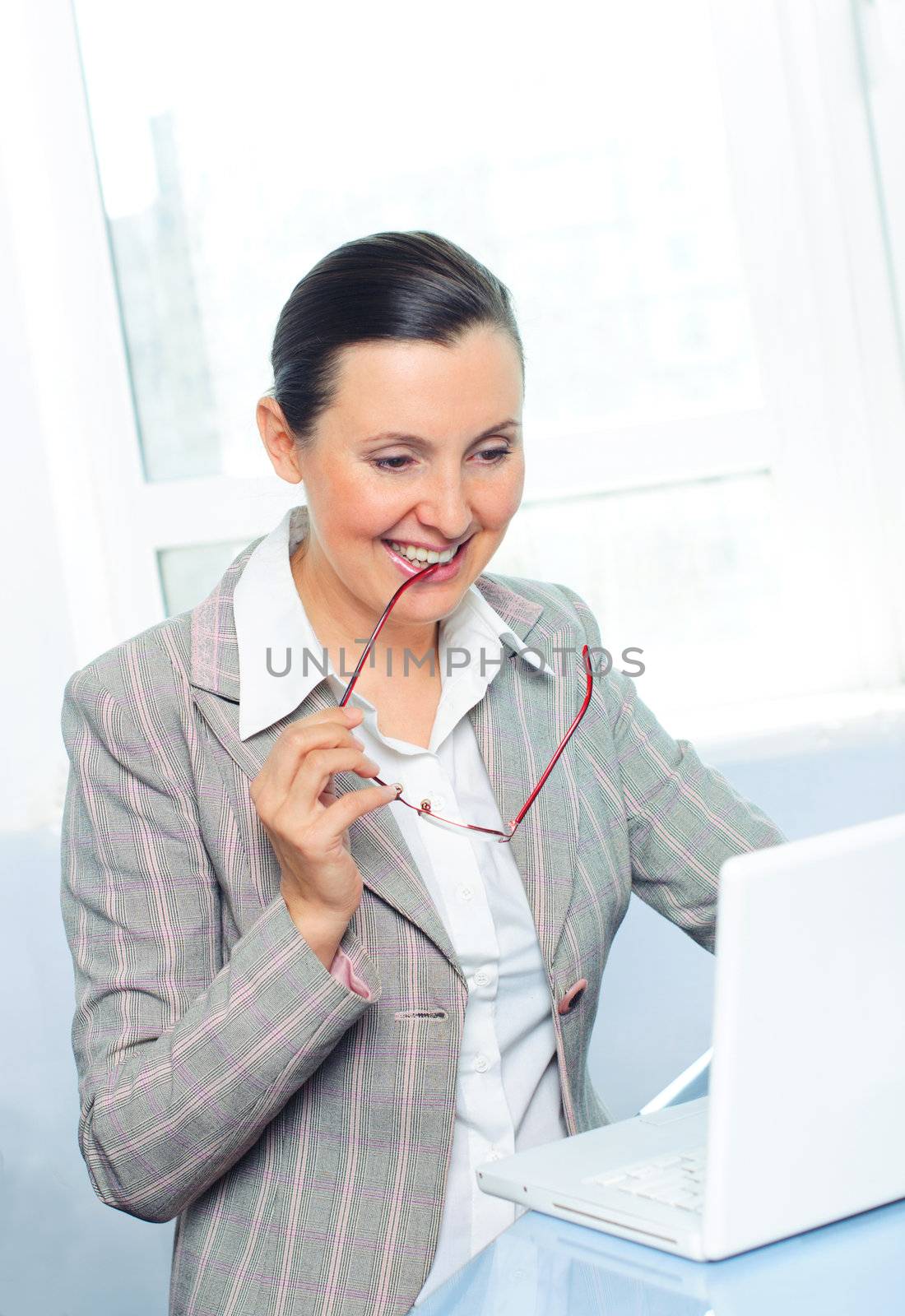 smiling young business woman with glasses using laptop by maxoliki