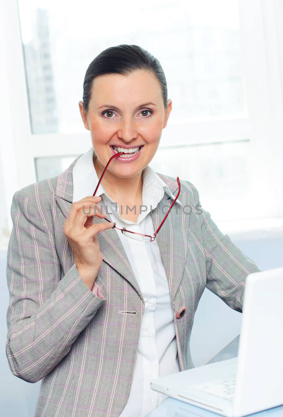 smiling young business woman with glasses using laptop by maxoliki