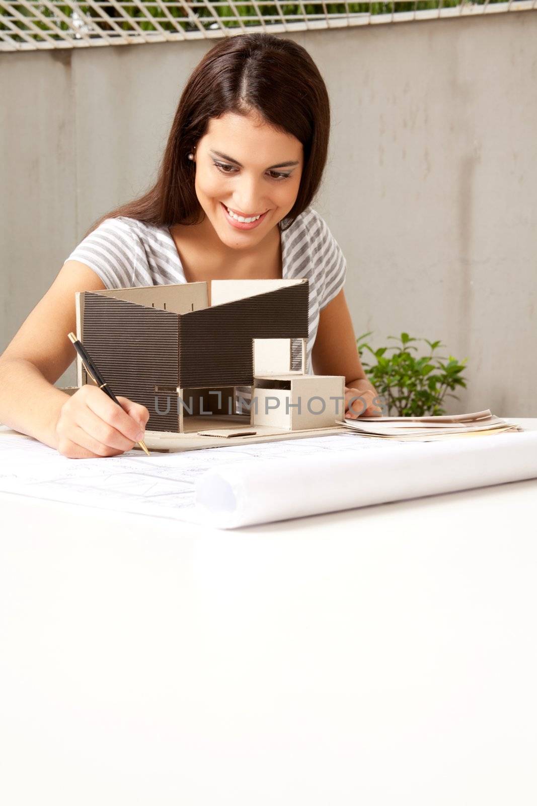 A young female architect working on a model and blueprints