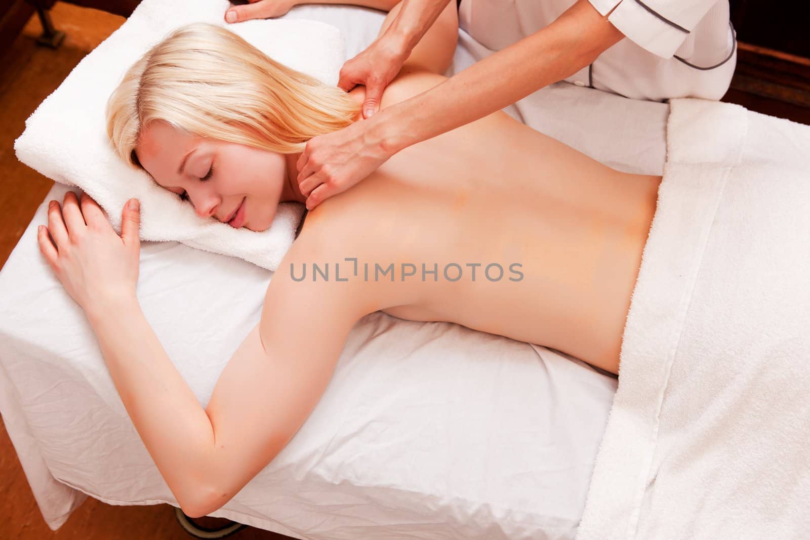 A blond caucasian woman receiving a shoulder massage at an old style spa