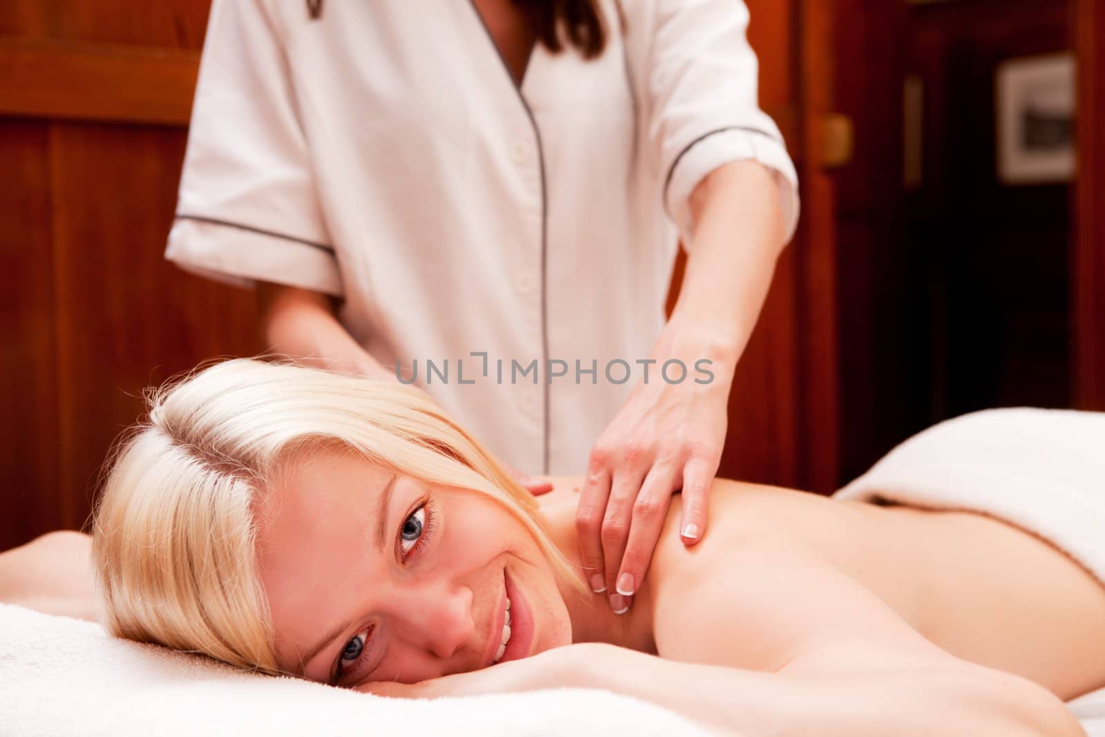 A young blond woman receiving a shoulder and back massage in an old style spa