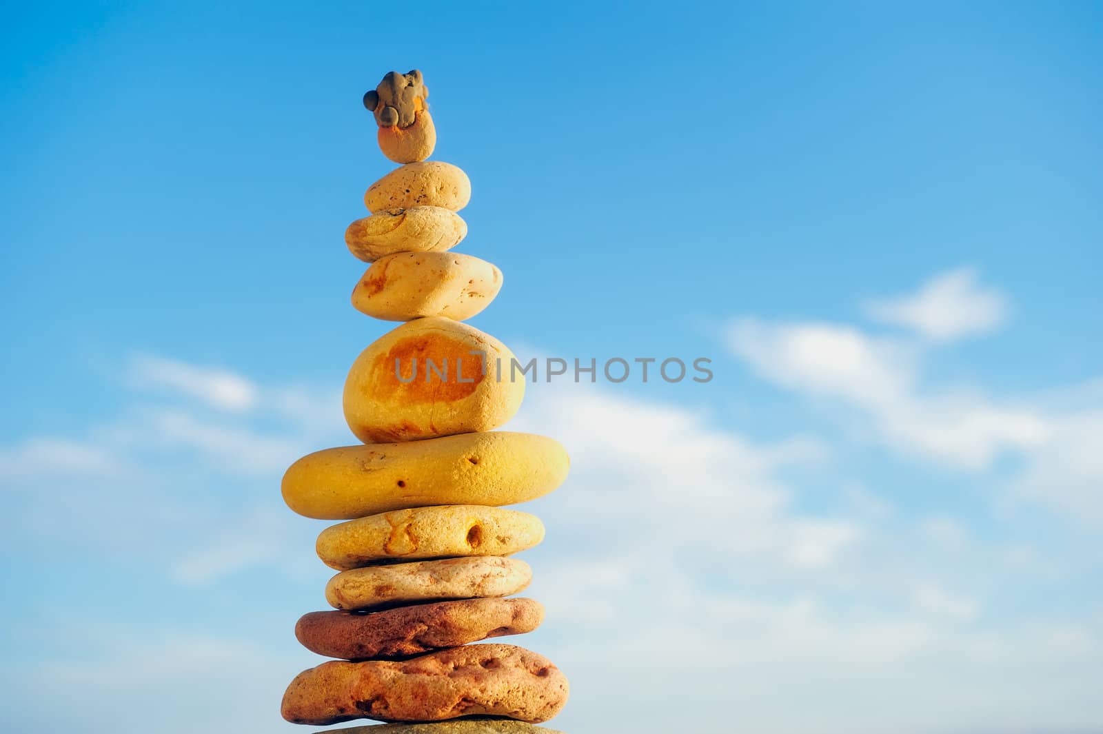 Balancing yellow pebbles each other on a sky background