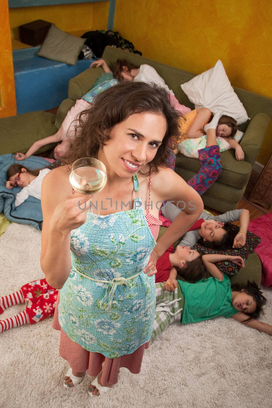 Relieved Hispanic woman drinking wine after kids fall sleep