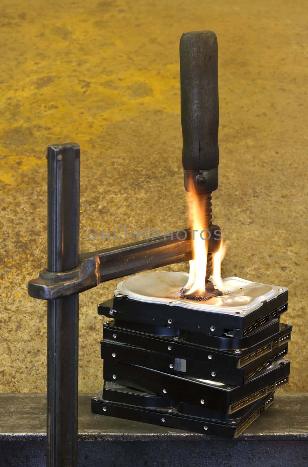 clamp pressing on burning stack of hard drives in rusty background