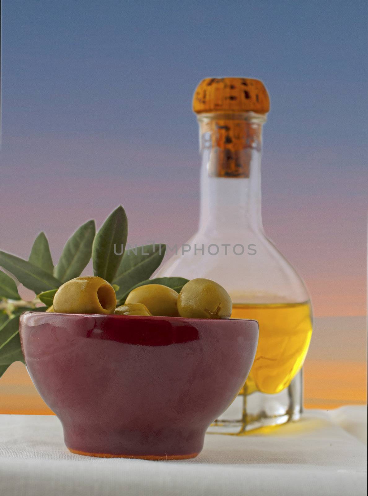 Olives in a cup with olive oil and olive branch on the background