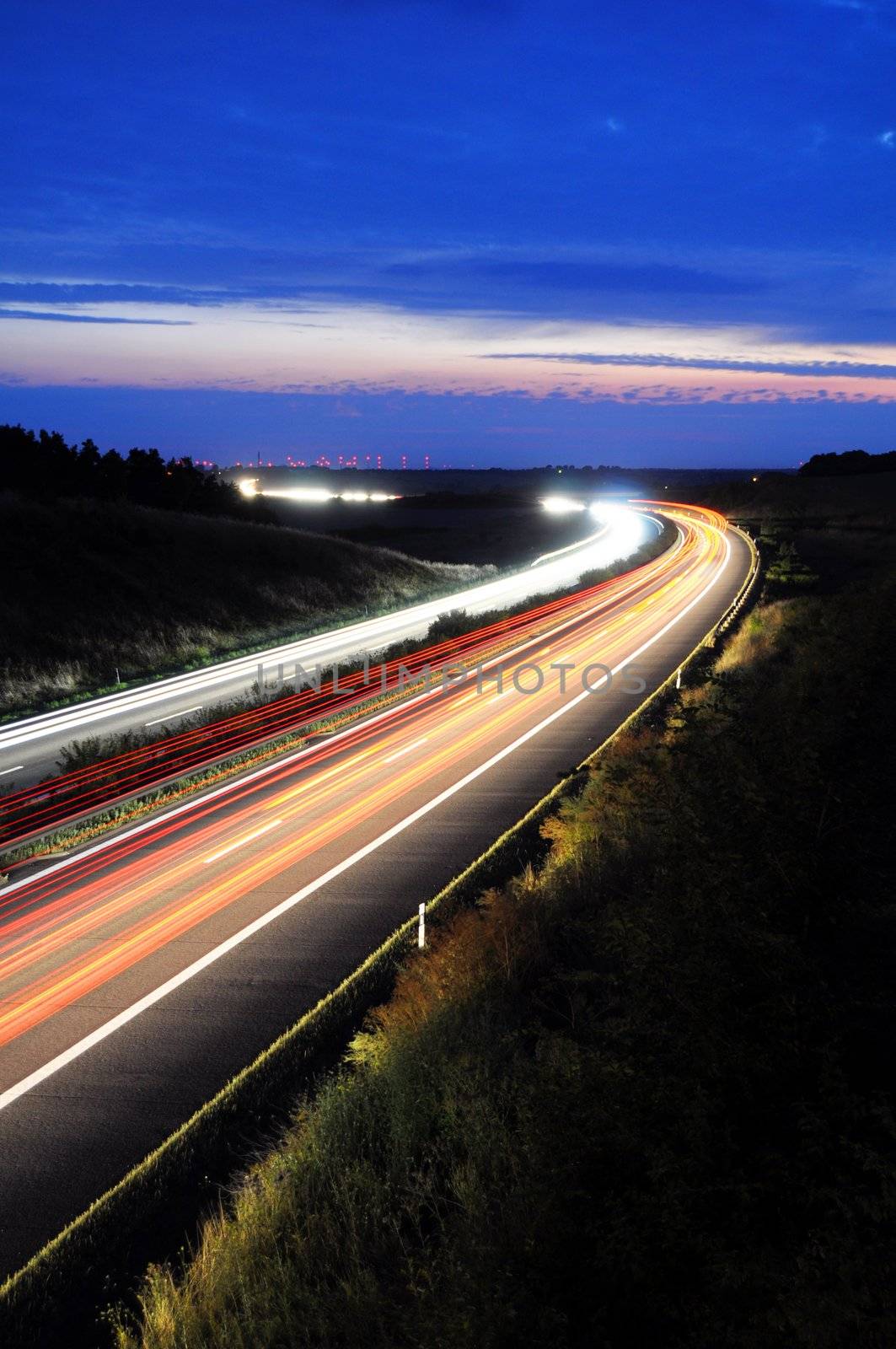 night traffic on busy highway with cars lights and blue sky