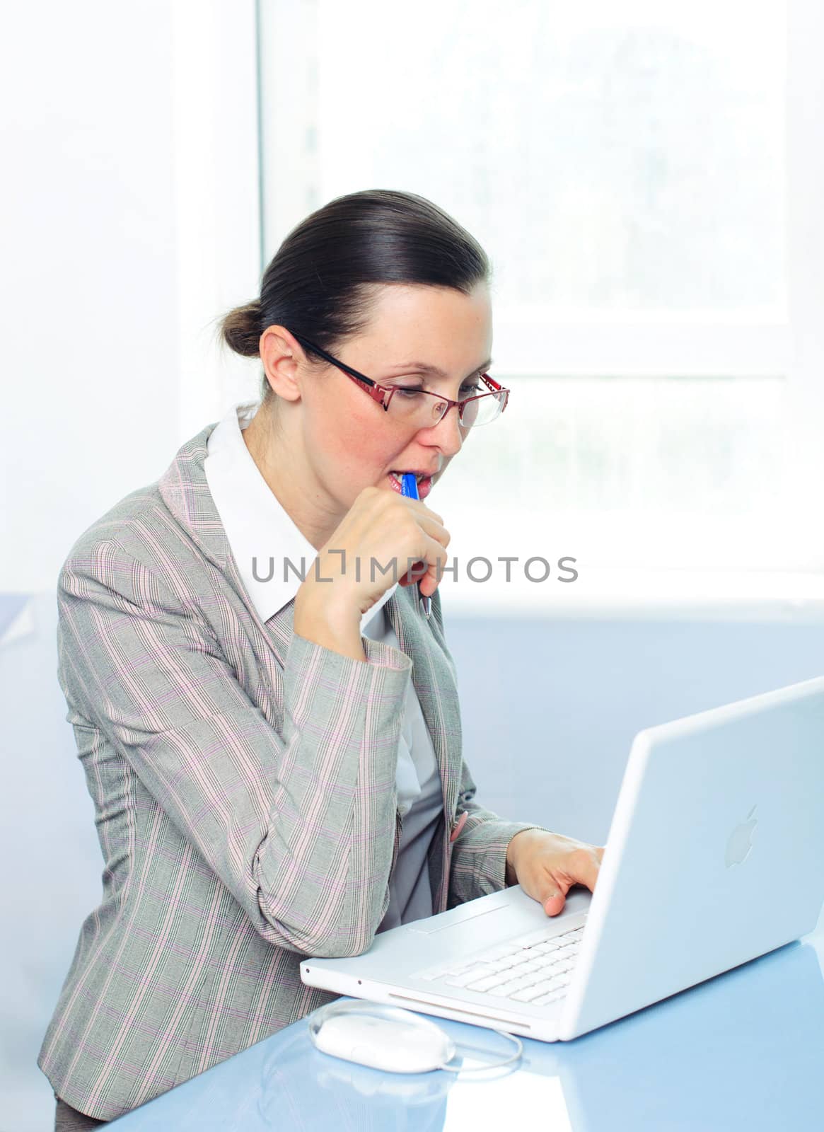 Attractive smiling young business woman with glasses using laptop at work desk