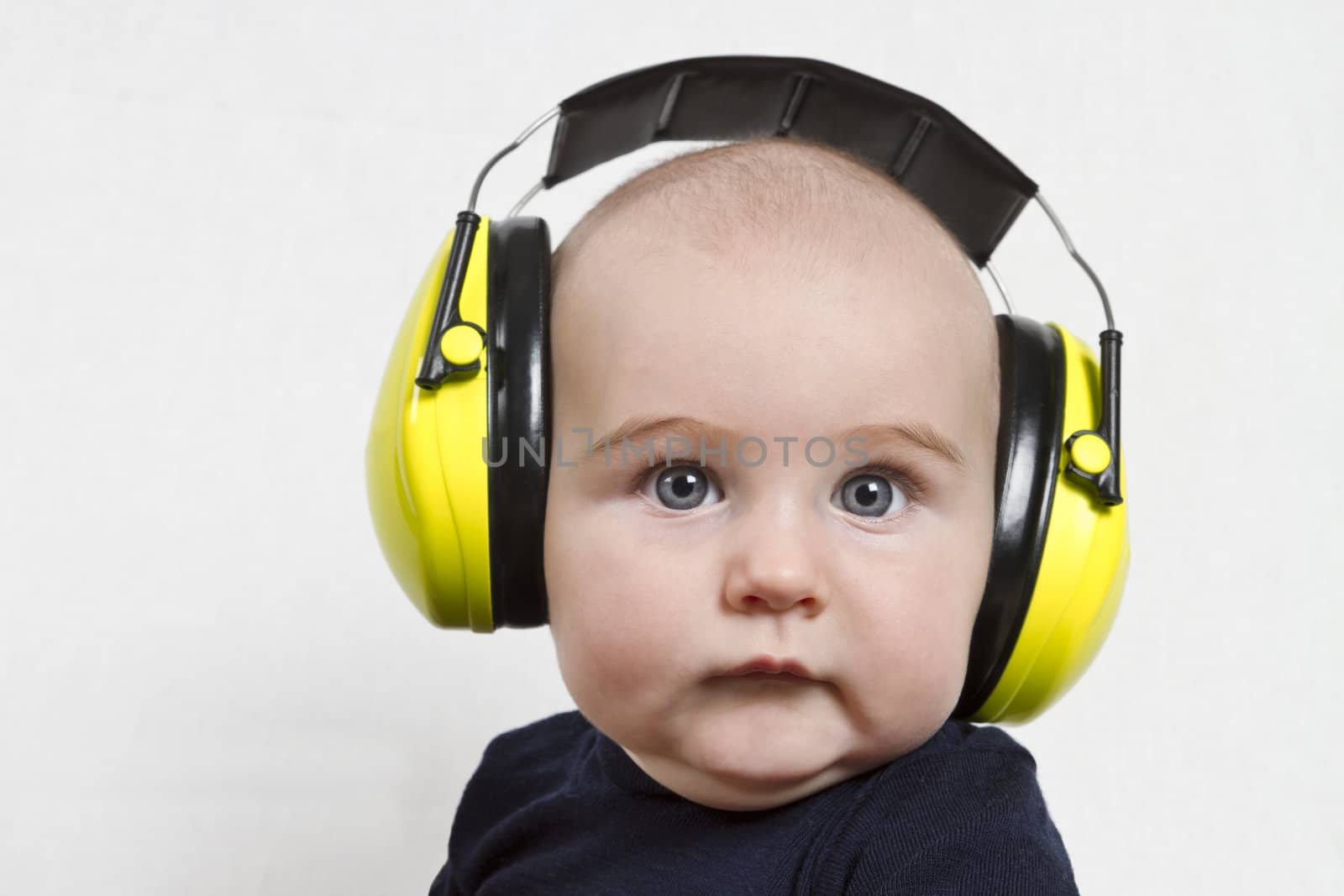 baby with yellow ear protection in loud environment. neutral grey background