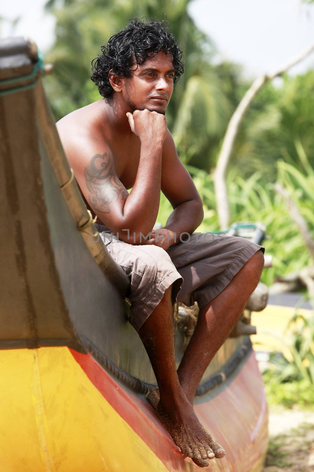 The young man sitting by a boat. Sri Lanka