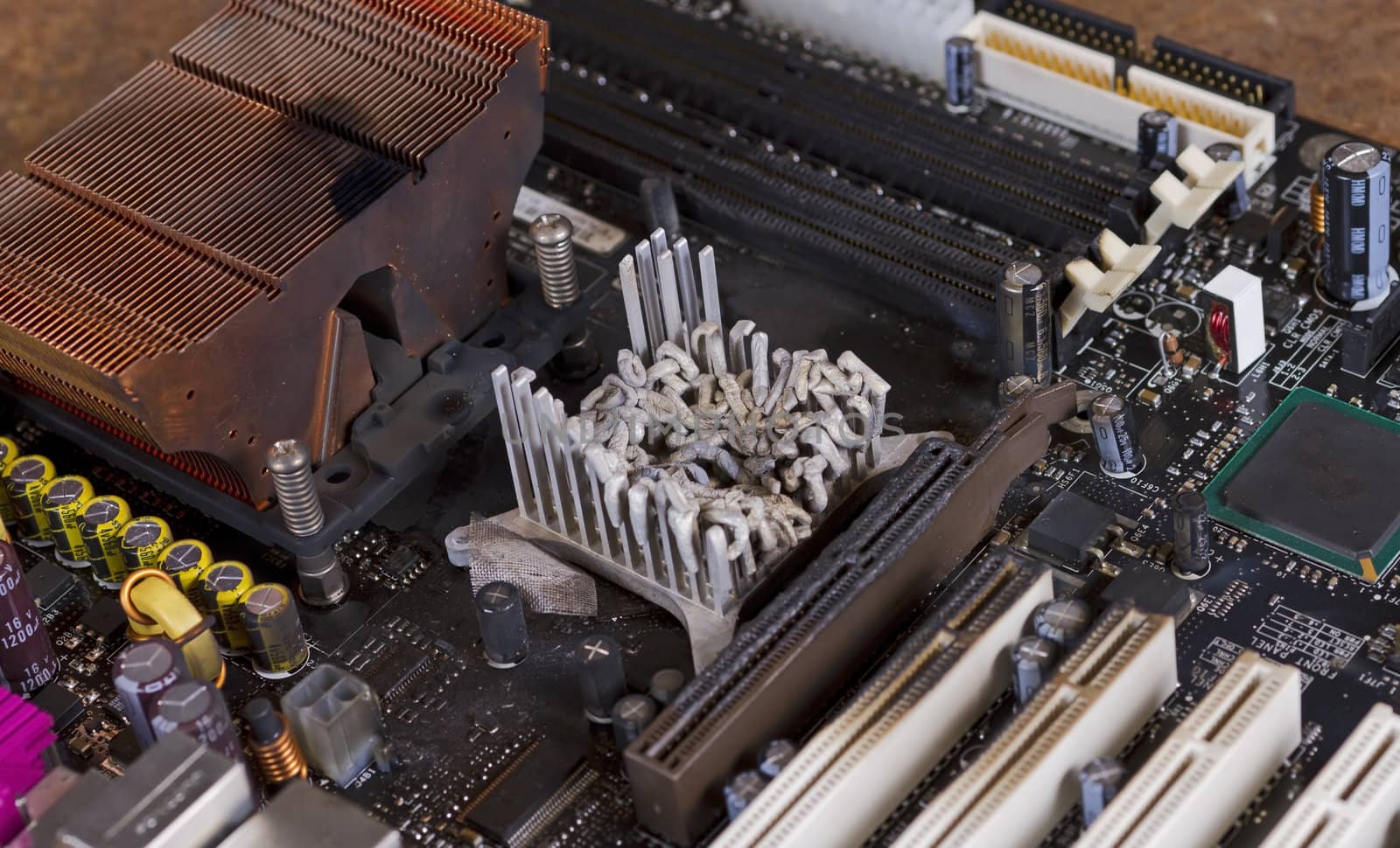 overheatetd computer part in close up shot. molten cooler and burned plastic