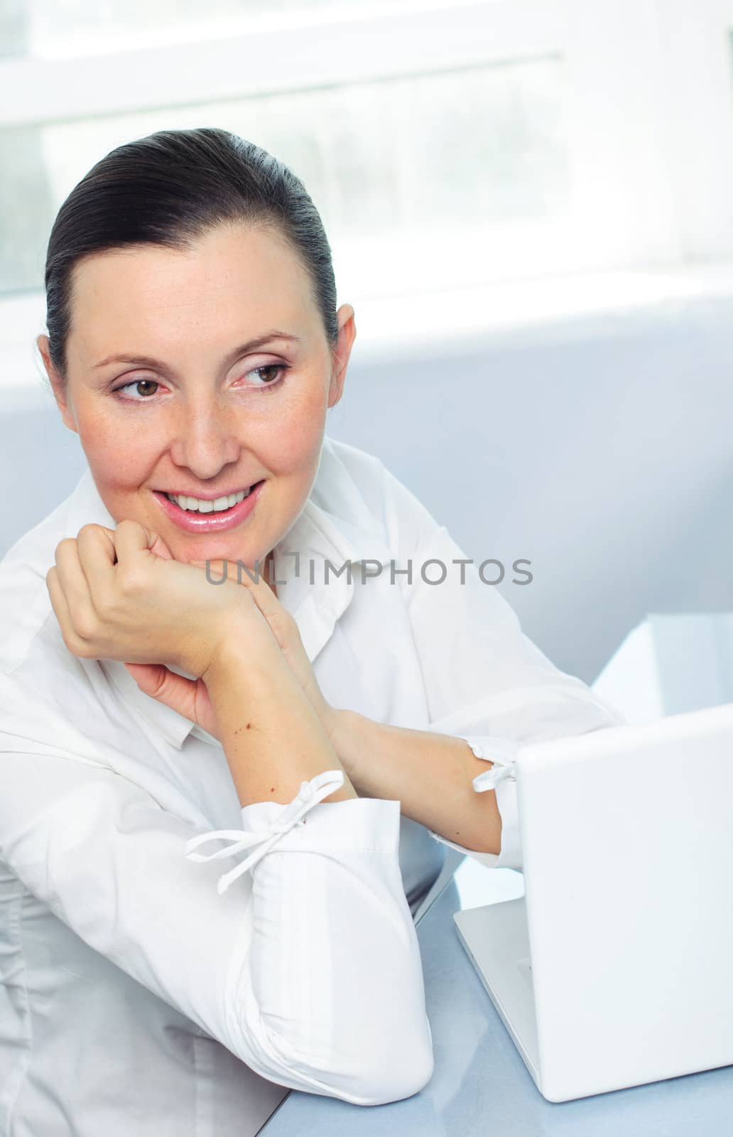 Attractive smiling young business woman using laptop at work desk