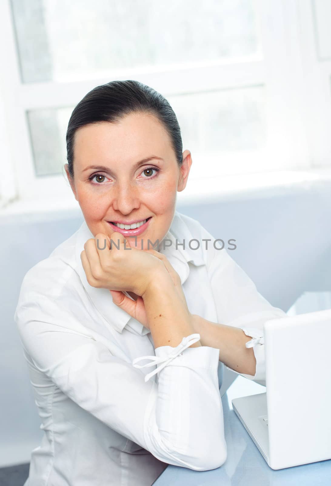 Attractive smiling young business woman using laptop at work desk