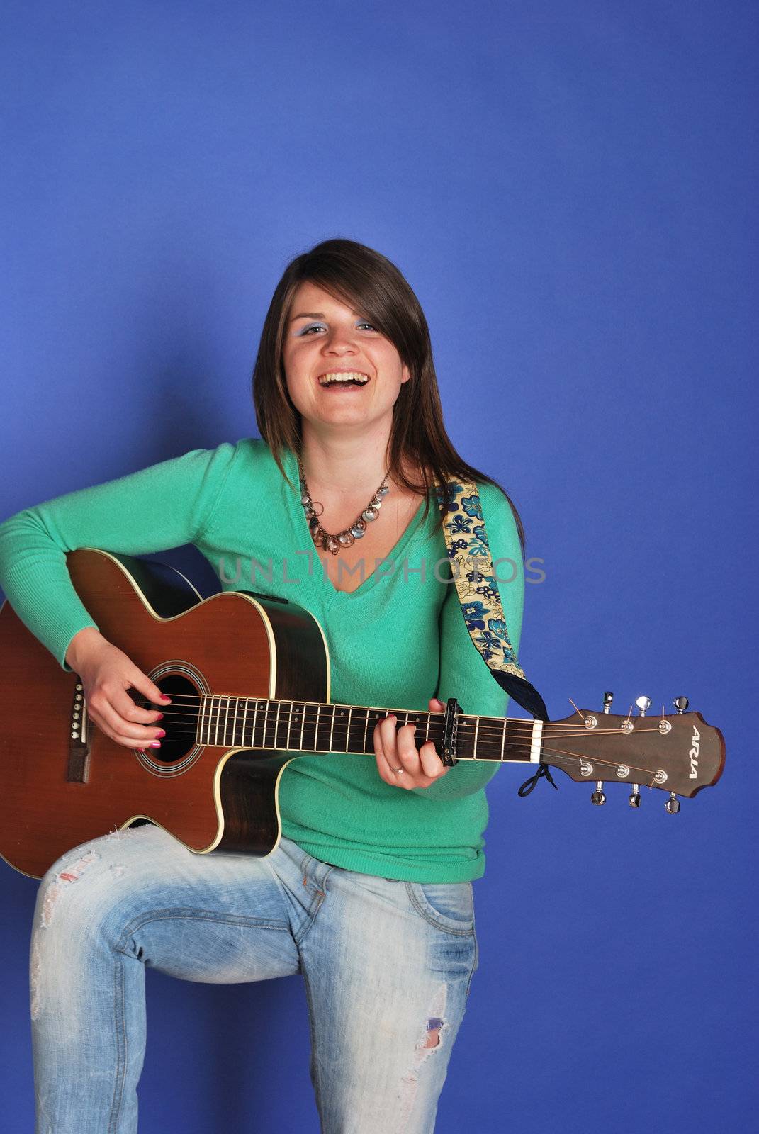 Pretty girl standing playing acoustic guitar