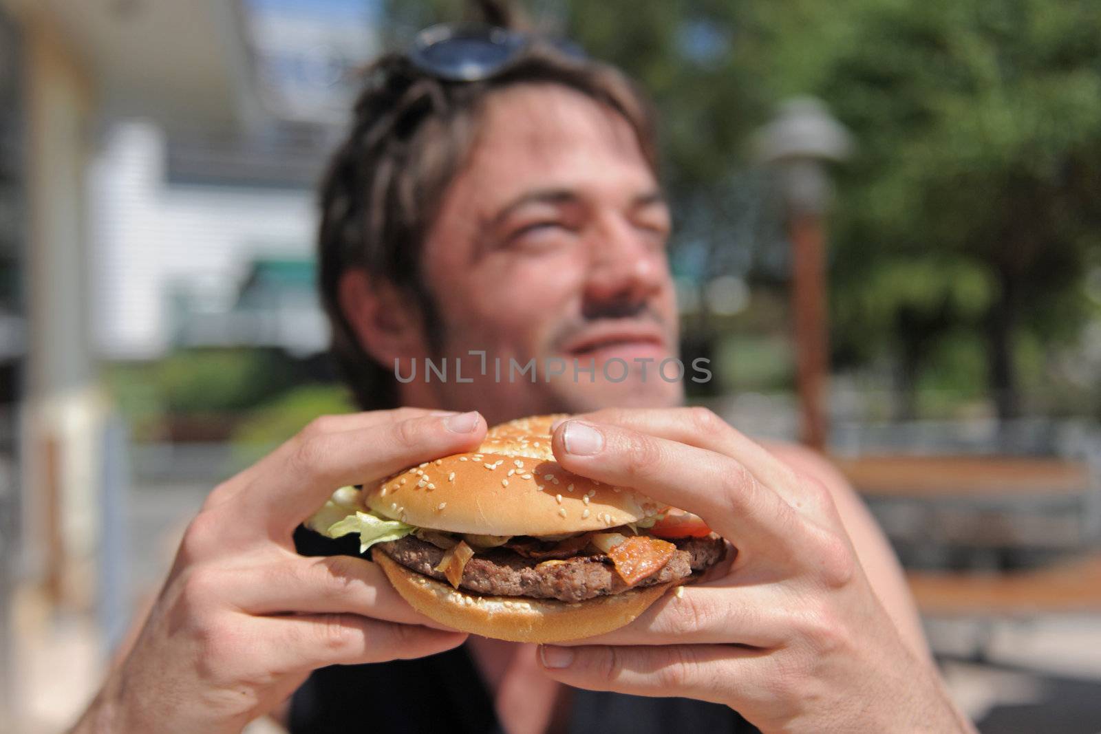 a man eating a hamburger in a fastfood, focus on the sandwitch