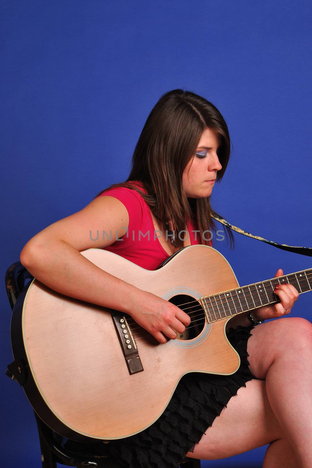 pretty girl in skirt sitting playing guitar