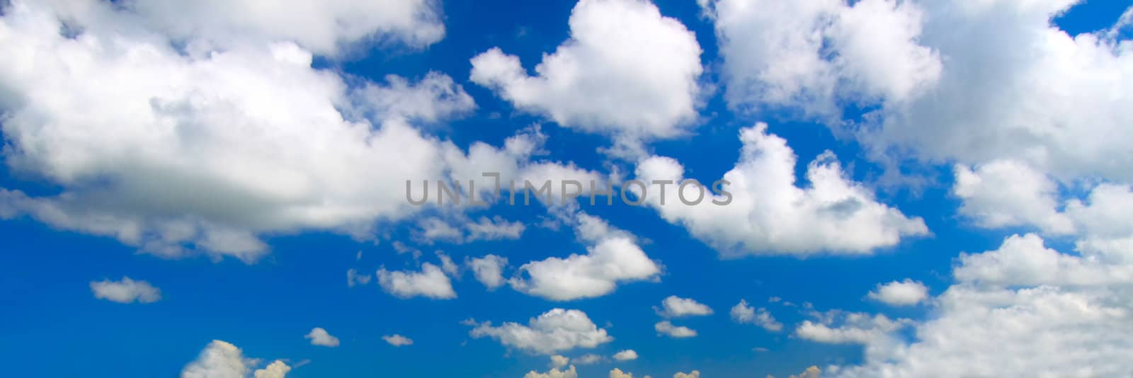 Panoramic view of scattered clouds against a bright blue sky.