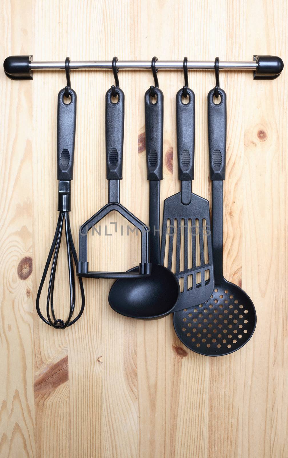 Set of black modern kitchen utensil hanging on wooden background