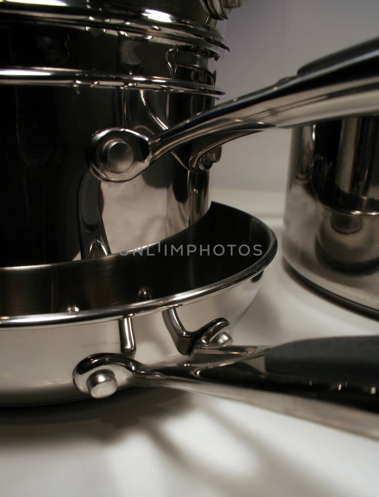 A pile of stainless steel pots and pans on white.
