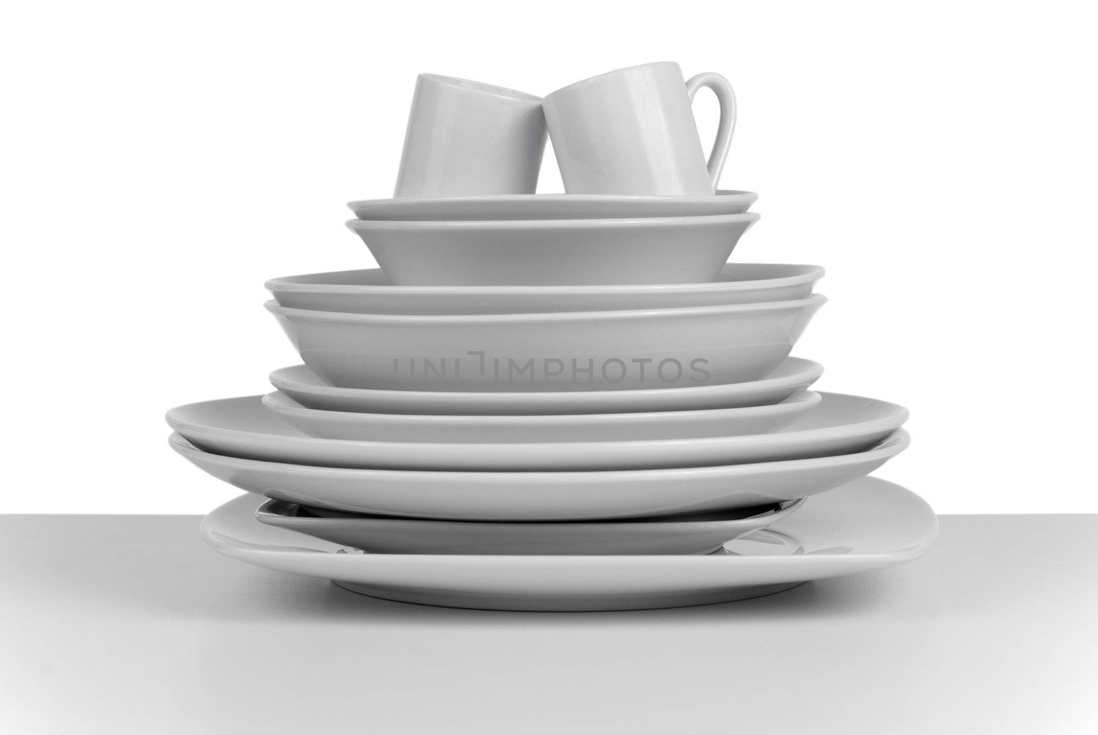 Pile of clean empty dishes and cups on white background.
