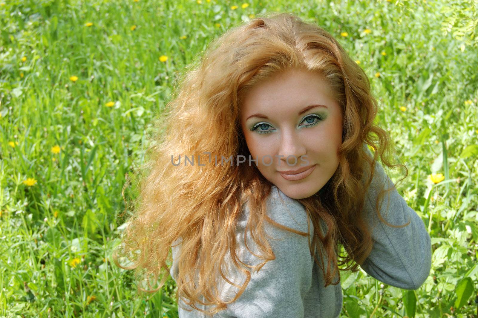 Beautiful red-haired girl over green grass